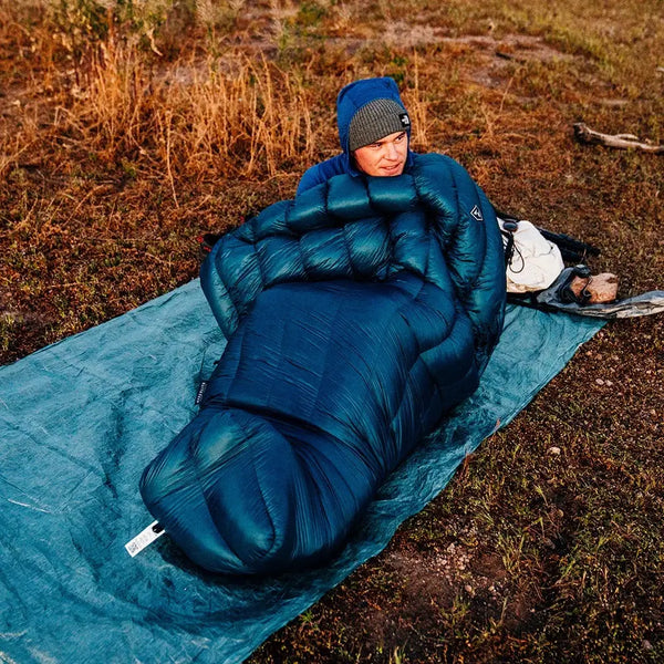 Hyperlite Mountain Gear 20-Degree Quilt in blue used by a camper outdoors