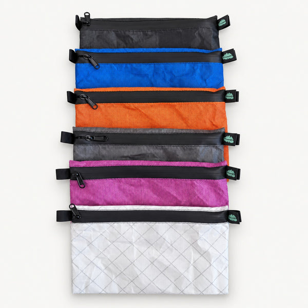 Six OUTDOORLINE Ultralight Wallet Large zippered pouches stacked, showing all colour options