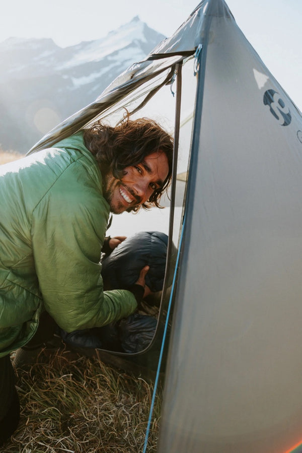 Gossamer Gear The One V2 – hiker in green jacket peeking out of the tent flap at sunrise