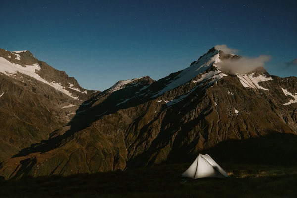 Gossamer Gear The One V2 pitched and lit up at night against a starry mountain skyline