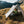 Gossamer Gear The One V2 – hiker sitting inside on a grassy hillside with mountains behind, boots outside