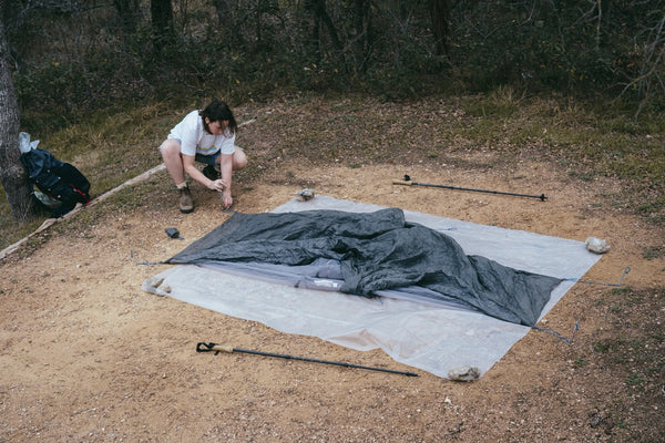 Gossamer Gear Polycro Ground Cloth laid out under a packed tent, trekking poles nearby
