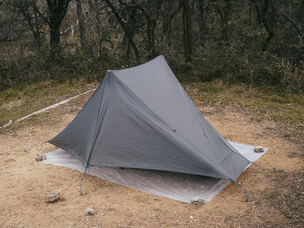 Gossamer Gear Polycro Ground Cloth under a fully pitched tent in a forest clearing